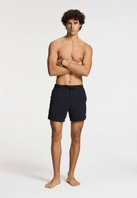 Black swim shorts made of lightweight fabric, featuring an elastic waistband with drawstring, mid-thigh length, and no visible patterns.