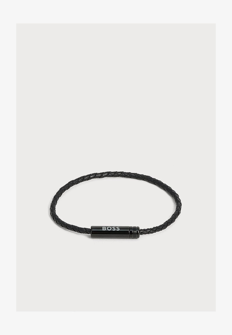 Bracelet en cuir tressé noir avec fermoir cylindrique gravé du mot "BOSS" en lettres argentées.