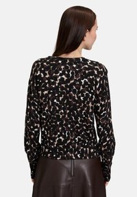 Sweter z dzianiny w czarno-brązowy wzór leopardzi, z długimi rękawami i ściągaczem na dole, prezentujący teksturowany wzór i gładkie wykończenie.