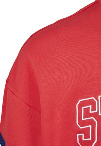 Rotes Baumwoll-T-Shirt mit Rundhalsausschnitt, kurzen Ärmeln und weißen gestickten Text auf der Vorderseite. Der Text ist für den Kontrast umrandet.