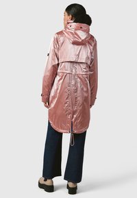 Ilga, lengva rožinė blizganti lietpaltis su šonu susiaurinančia juosta, kapišonu ir apvaliu kraštu. Yra reguliuojami rankogaliai ir nugaros ventiliacija.