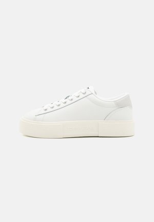 White leather sneaker with a textured rubber sole, rounded toe, and gray accents. Features a branded side and six eyelets for laces.