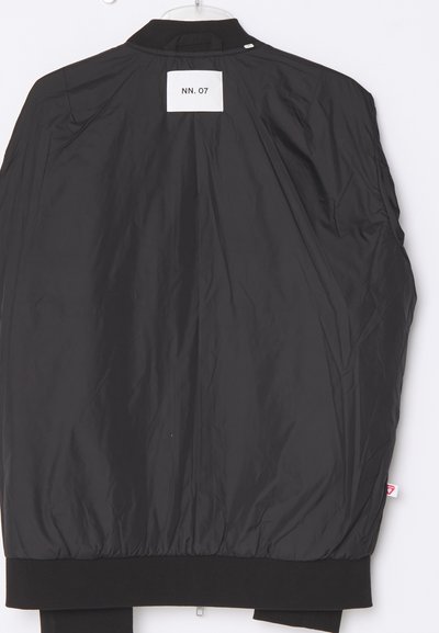 Schwarze Bomberjacke mit glatter Textur, gerippten Bündchen und einem Rückenetikett mit der Aufschrift "NN. 07." Verfügt über eine Aufhängeöse am Kragen.
