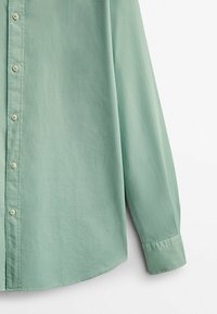 Hellgrünes Langarmhemd aus weichem Stoff, mit durchgehendem Knopfverschluss, abgerundetem Saum und Manschettendetails. Glatte Textur mit klassischem Schnitt.