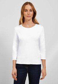 Witte, lange mouwen crew neck t-shirt van katoen. Heeft een gladde textuur en een fitted pasvorm, gecombineerd met donkere spijkerbroeken.