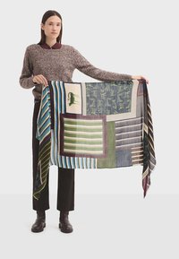Bufanda de patrón multicolor que presenta bloques de rayas, tonos sólidos y diseños bordados en verde, azul y burdeos sobre una tela texturizada.