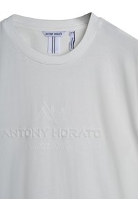 Witte katoenen T-shirt met een ronde hals, reliëf logo en tekstontwerp, voorzien van extra merklabels en een gladde textuur.