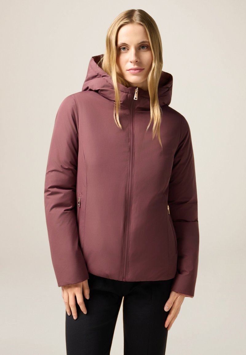 Bordeauxrote isolierte Jacke mit Kapuze, mit Reißverschluss vorne und schrägen Seitentaschen. Glatte Textur und figurbetontes Design.