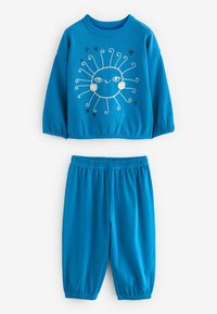 Completo due pezzi in cotone blu con una texture a costine. La parte superiore ha maniche lunghe e una grafica solare con stelle, mentre i pantaloni hanno una vita elasticizzata.