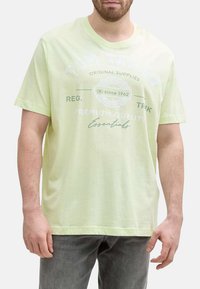 T-shirt en coton vert clair à manches courtes, avec texte imprimé et détails de logo. Encolure ras du cou standard et coupe décontractée.