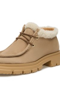 Stivali ankle in suede beige con una morbida fodera crema, punta rotonda e suola piatta in gomma con scanalature profonde e occhielli dorati per i lacci.