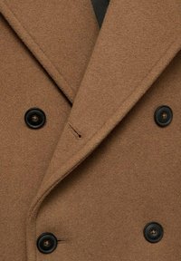 Bruine wolmix jas met een dubbelzijdig ontwerp, brede revers en zwarte knopen. Soepele textuur met een strakke, op maat gemaakte afwerking.