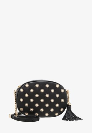 Zwart ovale crossbodytas met gouden zonnestraal-studs, gouden kettingband en zwarte kwastdetail tegen een witte achtergrond.