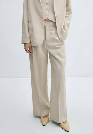 Beige maßgeschneiderter Anzug mit einem doppelt geknöpften Blazer, geraden Hosen und einem kurzen Weste. Glattes Material mit dezentem Glanz.