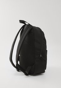 Svart ryggsekk med rektangulær form, laget av holdbart stoff. Har mesh-detaljer, justerbare stropper og en sidelomme med glidelås.