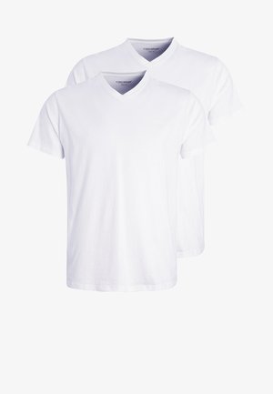 T-shirt en coton blanc avec un col rond associé à un legging noir près du corps. La tenue présente un design simple et minimaliste.