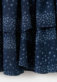 Donkerblauwe stof met kleine, lichtblauwe bloemenpatronen, gedrapeerd in zachte plooien.