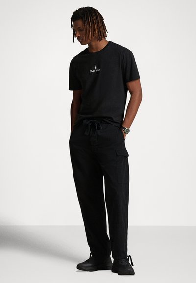 Svart t-shirt i bomull med rund halsringning och broderad logotyp, kombinerad med svarta cargobyxor med knytbar midja och sidofickor.