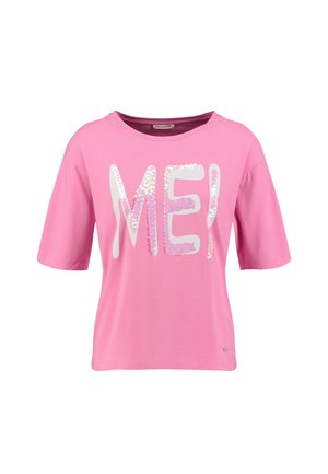 Chemise rose à manches courtes avec col rond, présentant de grandes lettres blanches et roses avec des paillettes formant "ME!" sur le devant.