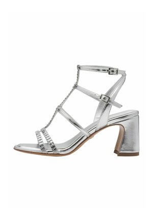 Zilveren sandaal met hoge, stevige hak. Voorzien van een metalen afwerking, meerdere bandjes en strass-steentjes over het teengebied.