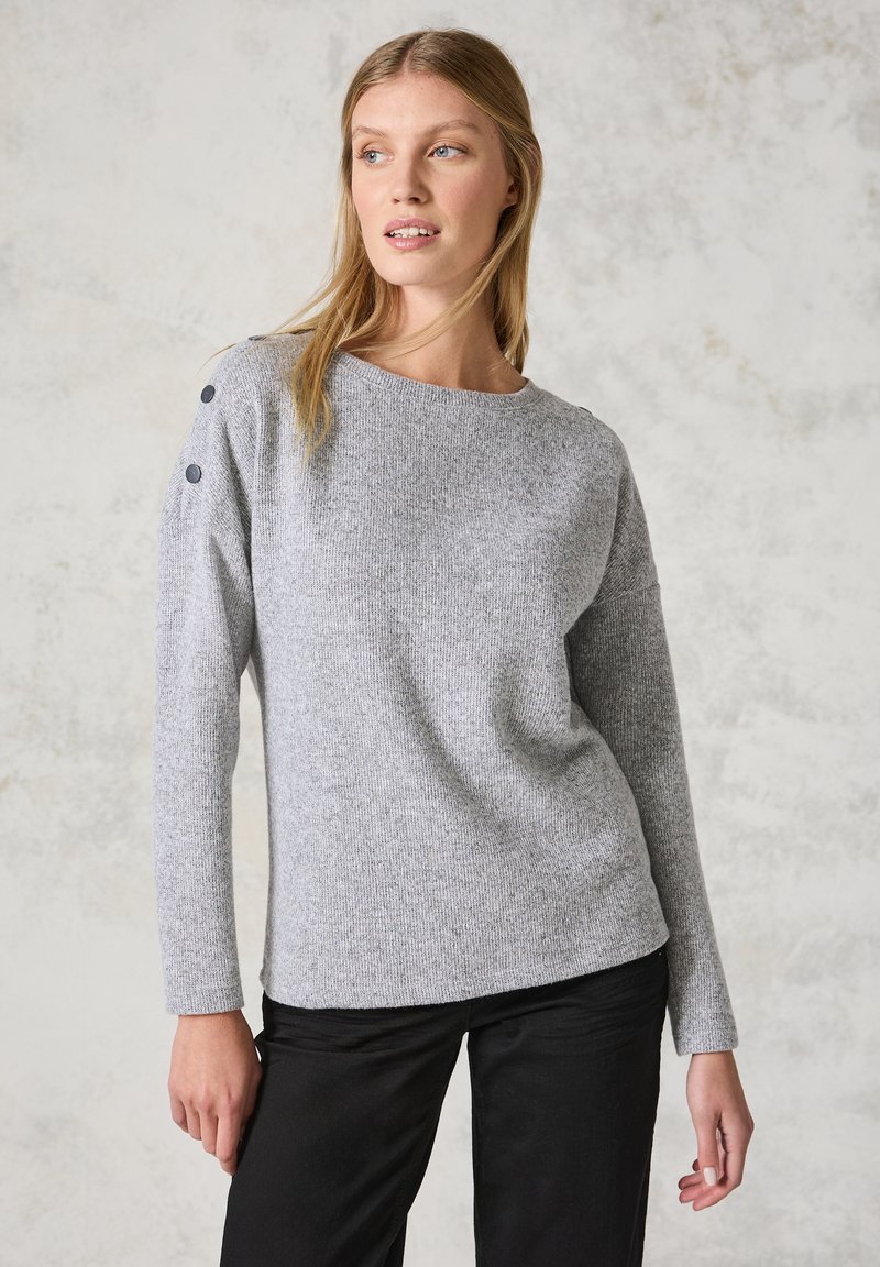 Grauer Strickpullover mit einem Schiffs-Ausschnitt, ausgestattet mit Knopfakzenten an der Schulter und langen Ärmeln, kombiniert mit schwarzen Hosen.