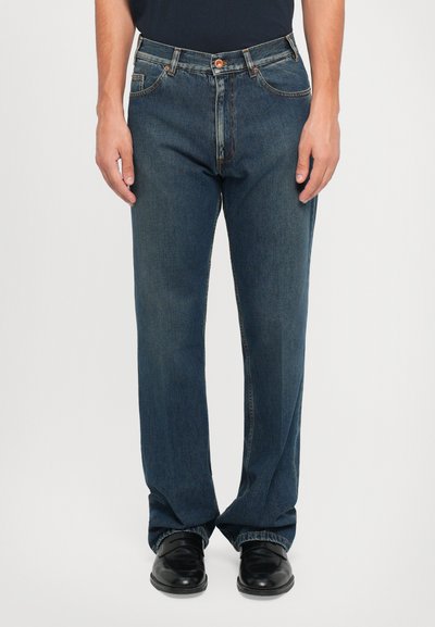 Blauwe denim jeans met een rechte snit, vijf-pocket ontwerp, contrasterende stiksels en een sluiting met een knoop aan de voorkant. Gecombineerd met zwarte schoenen.