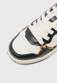 Sneaker featuring a black leather toe cap, white mid-panel, and leopard print accents. Textured black and white laces complete the design.