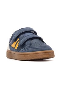 Zapatillas de velcro azules con acentos amarillos y blancos, que cuentan con una suela de goma texturizada y un diseño de puntera perforada para mayor transpirabilidad.
