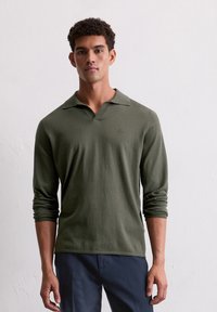 Polo à manches longues de couleur vert foncé, en matériau doux, avec un col classique et un logo brodé sur la poitrine. Design épuré.