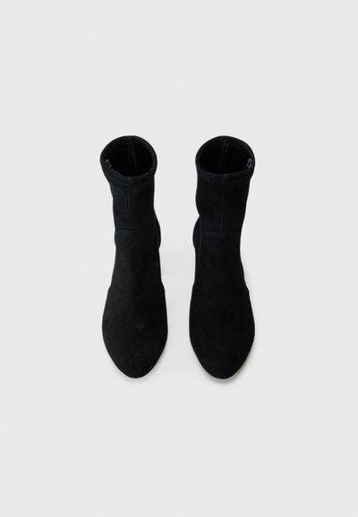 Botine negre din suede, cu vârf ascuțit și siluetă ajustată. Designul prezintă cusături fără sudură și o textură netedă.