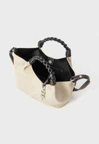 Beige ruskind taske med sorte fletremme og sølvhardware. Åben top, rummeligt indre med sidelommer. Kontraststing med detaljer.