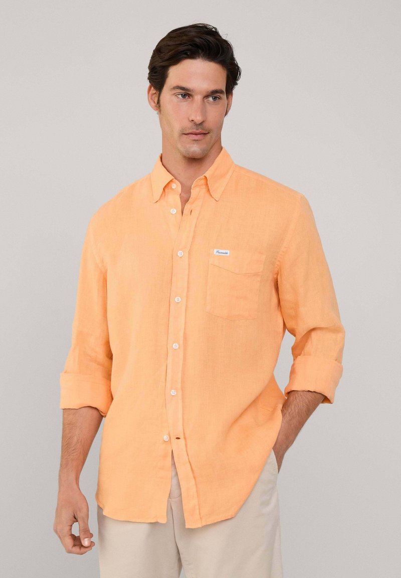 Lichtoranje linnen shirt met button-down kraag, lange mouwen opgestroopt, enkele borstzak en witte labeldetail.