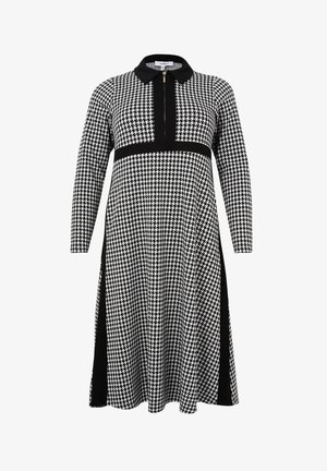 Robe midi à manches longues en pied-de-poule noir et blanc avec fermeture éclair à l'avant, col noir et panneaux verticaux noirs sur les côtés et la taille.