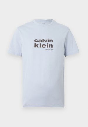 Világoskék pamut póló rövid ujjakkal, sötétbarna "calvin klein" és "New York City" felirattal az elején.