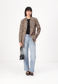 Sacou cu imprimeu leopardeau, top negru, blugi ușor albaștri și geantă neagră. Pantofii sunt balerini cu imprimeu leopardeau și curele.