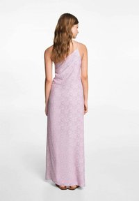 Dlouhá, bezramínková šaty v světle růžové barvě s květinovým vzorem. Měkká látka se elegantně splétá a má jednoramenný design.