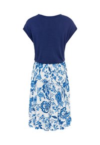 Blå kortärmad topp som övergår i en vit kjol med blå blommönster, med en avslappnad passform och mjuk bomullstyg.