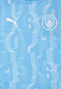 Maglietta sportiva azzurro chiaro con tessuto testurizzato, grandi numeri bianchi, logo Puma bianco e stemma del Manchester City.