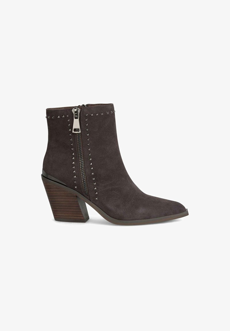 Stivale alla caviglia in suede marrone con punta affusolata, zip laterale, dettagli borchiati lungo la cerniera e tacco in legno affusolato.