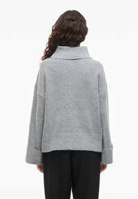 Grauer, übergroßer Pullover mit weitem Kragen, strukturiertem Strickstoff und langen Ärmeln. Hat eine cropped Länge und umgeschlagene Bündchen.