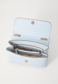 Borsa a tracolla in pelle blu chiaro con catene dorate, interno in tessuto beige, compartimenti con zip e aperti, e chiusura a scatto magnetico, aperta e vuota.