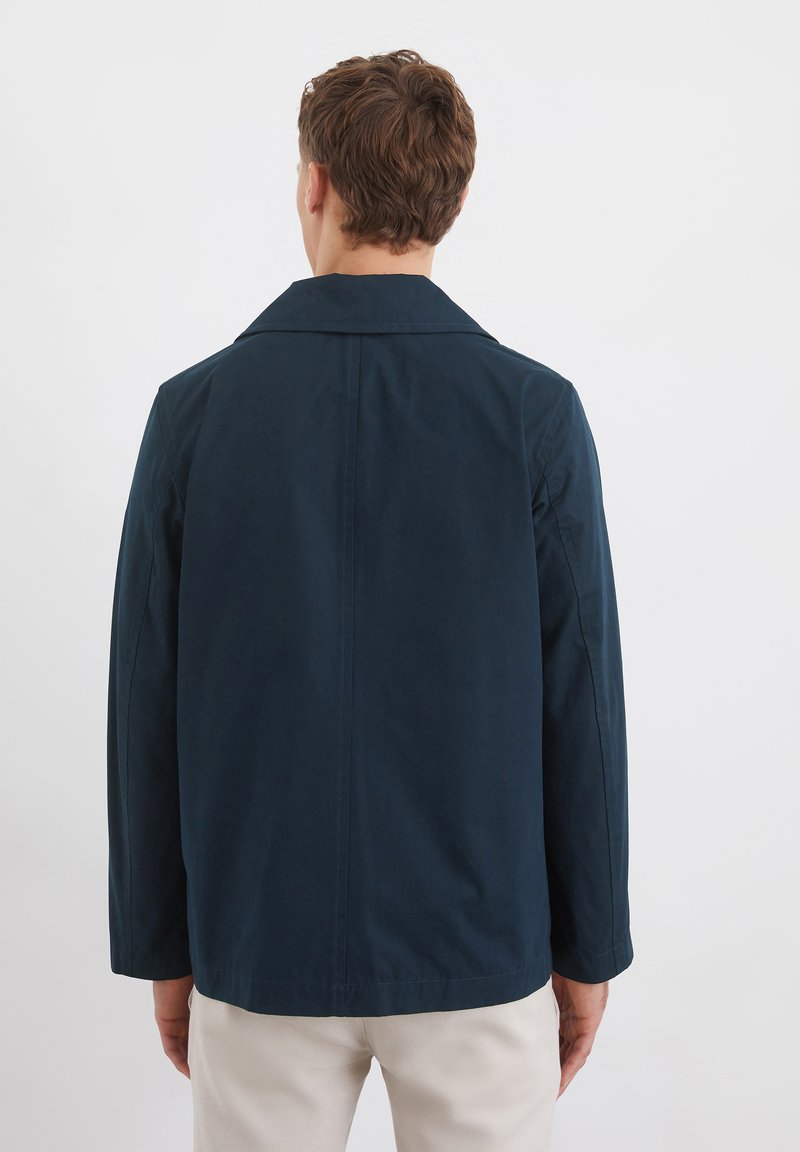 Dunkelblaue Baumwolljacke mit Reverskragen, langen Ärmeln und glatter Textur. Verfügt über eine taillierte Passform und dezente Nahtdetails.