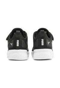 Chaussures de sport noires avec une tige en tissu texturé, semelles blanches et un logo Puma bien visible sur les talons et les côtés.