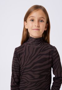 Bluzka z długim rękawem w ciemnobrązowym kolorze z czarnym wzorem tygrysich pasków. Posiada wysoki kołnierz i gładką teksturę tkaniny.