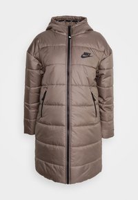 Padded brown parka with hood, black zipper, and side pockets. Features a subtle logo on the chest and horizontal quilted pattern.