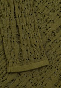 Olíva zöld kötött szövet, csipke mintával és nyitott munkával. Simaság jellemzi, az élein szabálytalan rojtozódással.