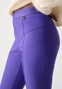 Paarse leggings van een gladde, rekbare stof, met een gestructureerde tailleband en een gestroomlijnde pasvorm met subtiele stikdetails.