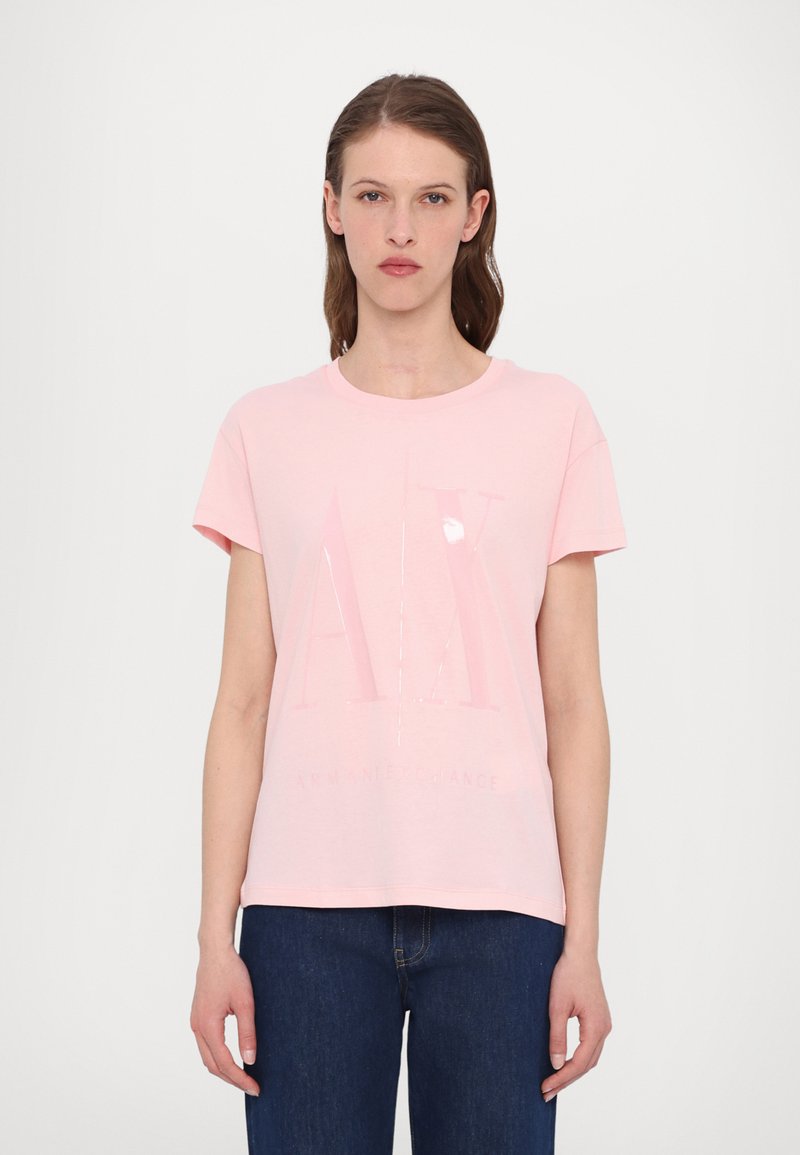 Gaiši rozā īsām piedurknēm T-krekls, izgatavots no mīksta auduma. Priekšpusē ir spīdīgs "AX" logos un "ARMANI EXCHANGE" teksts.