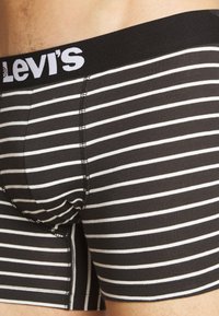 Boxer shorts de rayas blanco y negro con una cinturilla elástica negra que presenta el logo de Levi's; tejido suave y diseño ajustado.
