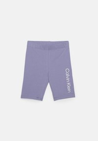 Lila bomullsbyxor för cykling med en åtsittande design, med en vit "Calvin Klein" logotyp på den nedre sidan och ett elastiskt midjeband.